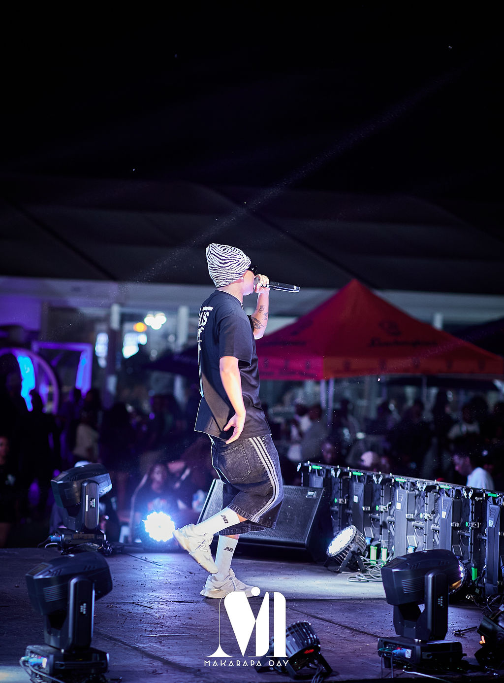 Makarapa Day stage at night, with a live performer, lights and the crowd